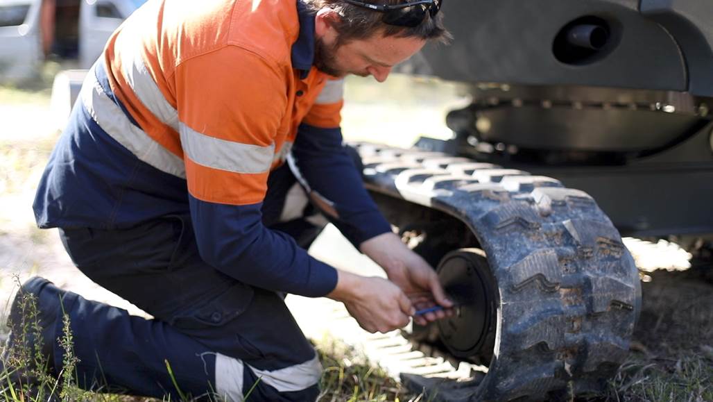 man is fixing the wheel of the excavator